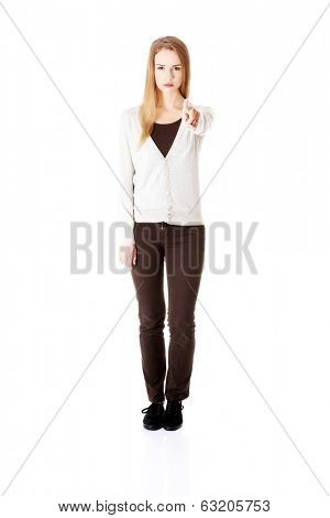 Beautiful casual woman pointing on you and warning or accusing of sth. Isolated on white.