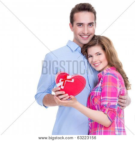Happy young couple with a gift in a studio isolated on a white background.