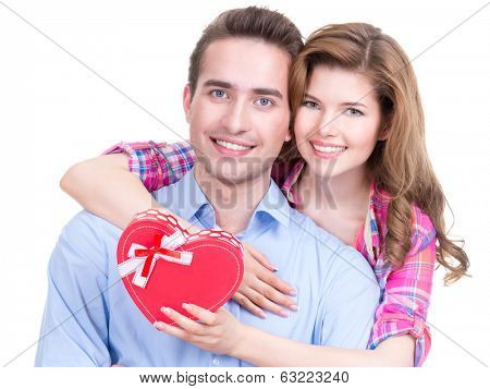 Happy young couple with a gift in a studio isolated on a white background.