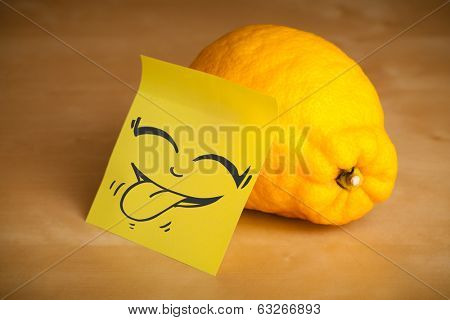 Drawn smiley face on a post-it note sticked on a lemon