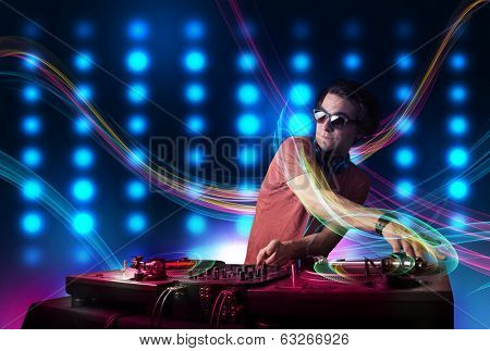 Attractive young Dj mixing records with colorful lights