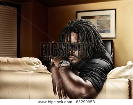 cool black man with dreads on leather couch.