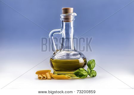 Glass bottle with olive oil penne pasta and basil leaves.