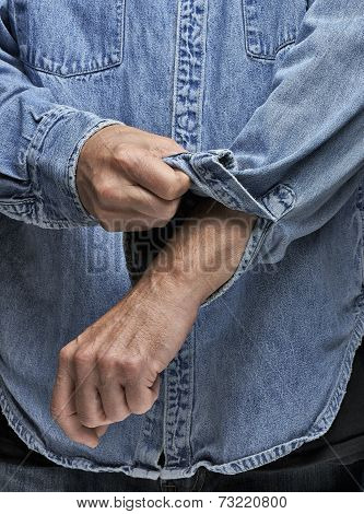 Man In Denim Shirt Rolling Up His Sleeves