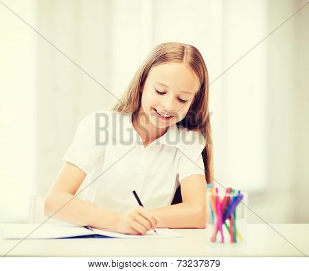 education and school concept - little student girl drawing at school