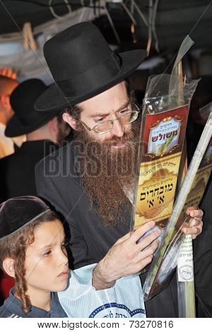 BNEY-BRAK, ISRAEL - SEPTEMBER 17, 2013: Middle-aged man with a red beard carefully chooses ritual plant - myrtle. Next to him stands a boy.  Grand Bazaar on the eve of the Jewish holiday