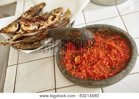 Sambal, special spicy chili paste in Indonesia, making on stone mortar to be eaten with another meal like fried fish