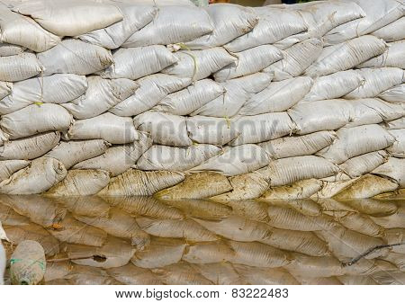 White Sandbags For Flood Defense And It's Reflection Brown Water