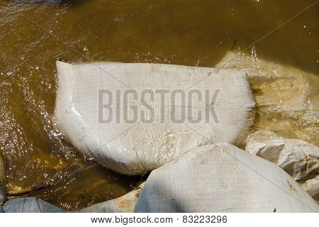 White Sandbags For Flood Defense And It's Reflection Brown Water