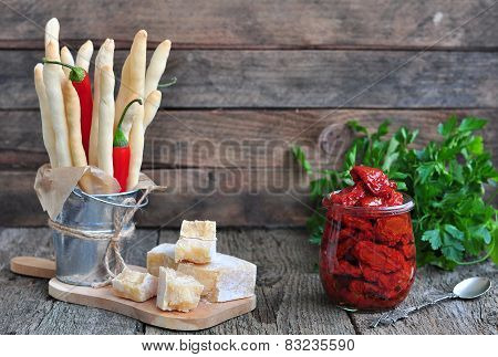 Handmade Grissini, parmesan cheese, salami, parsley and dried tomatoes on wood background