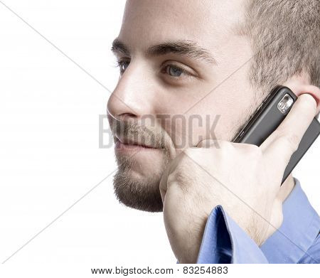 Concentrated young businessman using laptop and phone at office
