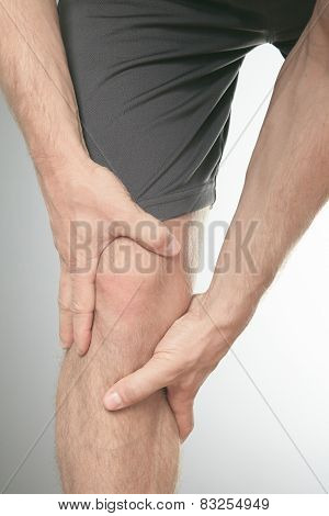 Man with both palm around knee cap to show pain and injury on kn
