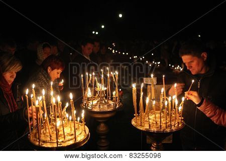 PRAGUE, CZECH REPUBLIC - MAY 5, 2013: Orthodox believers light candles during an Orthodox Easter night service in front of the Dormition Church at the Olsany Cemetery in Prague, Czech Republic.