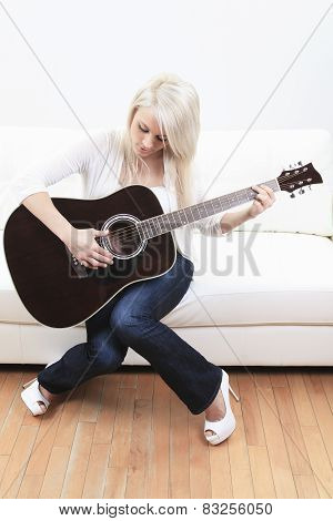 beautiful young woman on the couch with a guitar