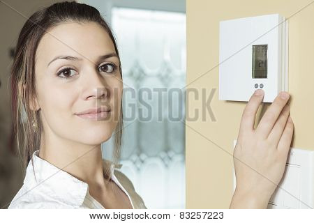 A woman set the thermostat at house.