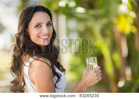 Pretty brunette drinking glass of water on a sunny day