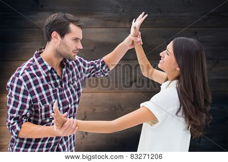 Fearful brunette being overpowered by boyfriend against wooden planks background