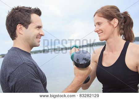 A Young, caucasian couple working out with dumbbells outside