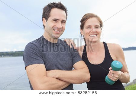 A Young, caucasian couple working out with dumbbells outside