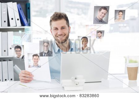 Handsome man working at his desk on laptop smiling at camera against profile pictures