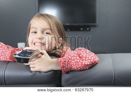 A cute little girl with remote control in front of TV.