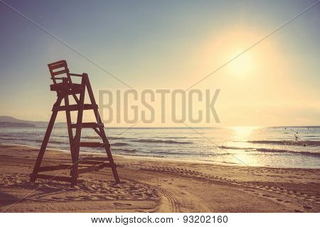 Baywatch chair in empty beach at sunset