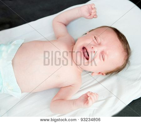 Nice newborn in diaper crying inconsolably