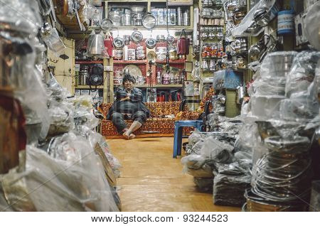 JODHPUR, INDIA - 07 FEBRUARY 2015: Shop owner with hat sitting on couch and resting before closing time. Post-processed with added grain and texture.