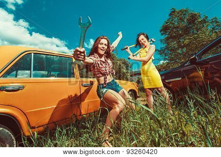 Cheerful Woman Mecanic Is Repairing A Car With The Wrench Another Woman Is Watching.