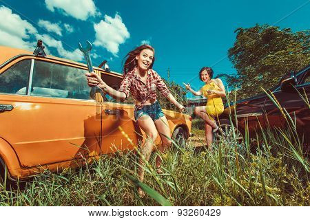 Cheerful Woman Mecanic Is Repairing A Car With The Wrench Another Woman Is Watching.