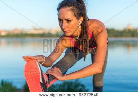 Athletic woman stretching her hamstring, legs exercise training fitness before workout outside on a