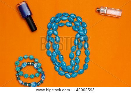 Woman Accessories Turquoise Necklace, Bracelet And Parfume On Orange Background