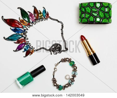 flat lay feminini accessories collage with glasses high heel shoes mascara lipstick bracelet earrings necklace and bow tie clips on white background.