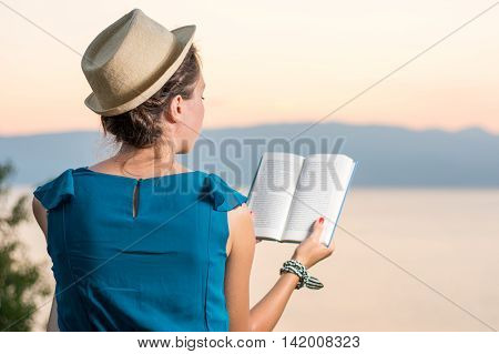 Woman Reading A Book With A Sunset View