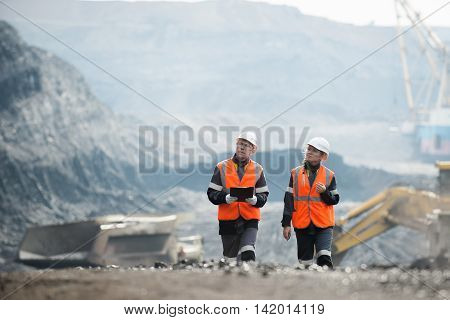 Two speacialists examining coal at an open pit
