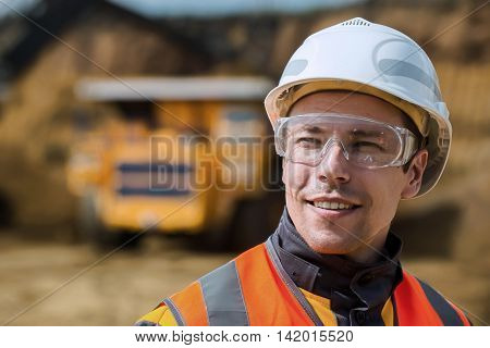 Mine worker with huge truck on the background in open pit