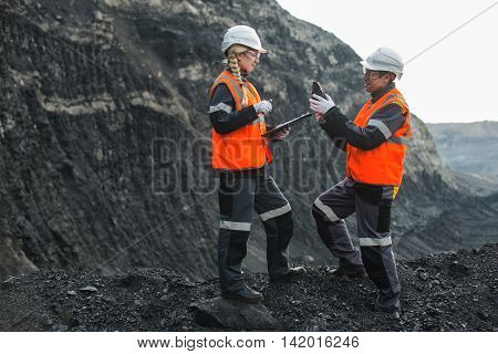 Two speacialists examining coal at an open pit