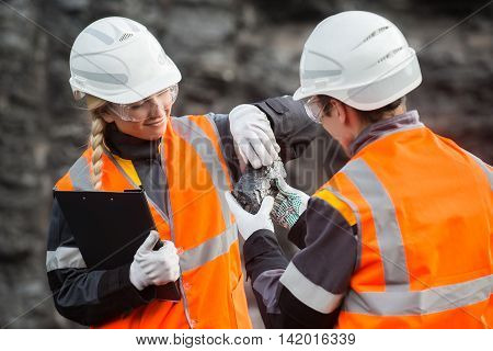 Two speacialists examining coal at an open pit