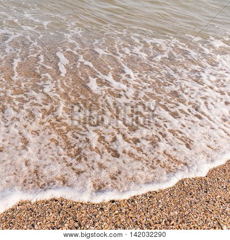 soft seawave with foam on sandy shore