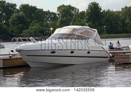 White yacht at anchor in the harbor and the young couple