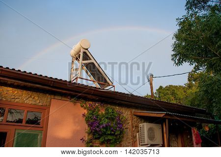 solar cell a building and a rainbow in the background of the clear sky