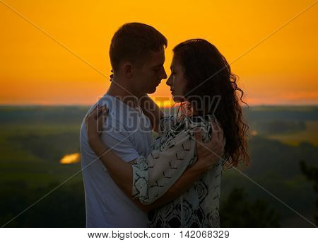 romantic couple at sunset on outdoor, beautiful landscape with bright yellow sky, love tenderness concept, young adult people