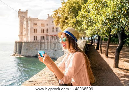 Young woman having fun photographing landscape near Miramare castle in northeastern Italy. Traveling in Italy
