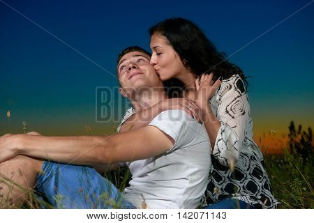 young romantic couple sit on grass and embrace on country outdoor, dark night sky, love concept, adult people