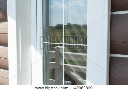 Plastic white window muntin bars with the reflection of the blue cloudy sky with green trees
