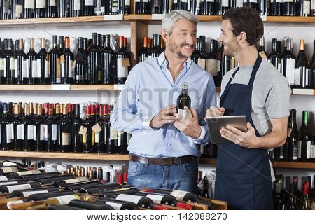 Salesman Using Digital Tablet While Customer Holding Wine Bottle