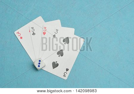 The different suits of a the number 3 card in a deck of cards displayed on a blue background with a dice