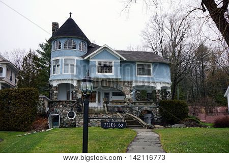 WEQUETONSING, MICHIGAN / UNITED STATES - DECEMBER 22, 2015: A lamppost, with an attached sign indicating the house number and owner's name, stands in front of a large blue mansion on Beach Road in Wequetonsing.