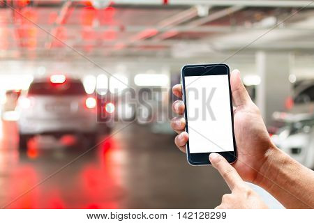Man with mobile smartphones, background blur parking under the building.