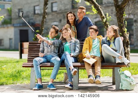 education, high school, technology and people concept - group of happy teenage students or friends taking selfie by smartphone and monopod